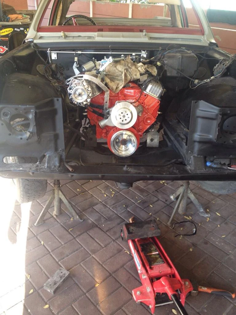 The red-finished V8 installed in the black engine bay, with front body panels still removed.